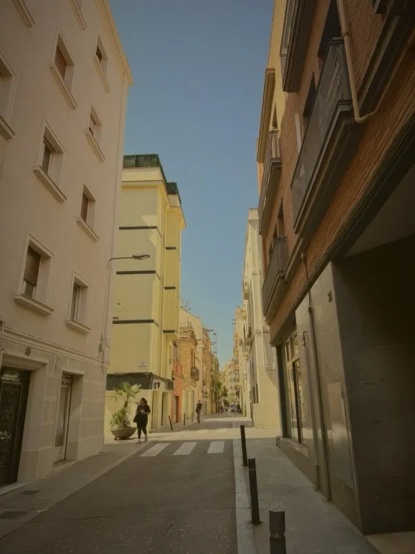 Looking up between Barcelona buildings into blue sky
